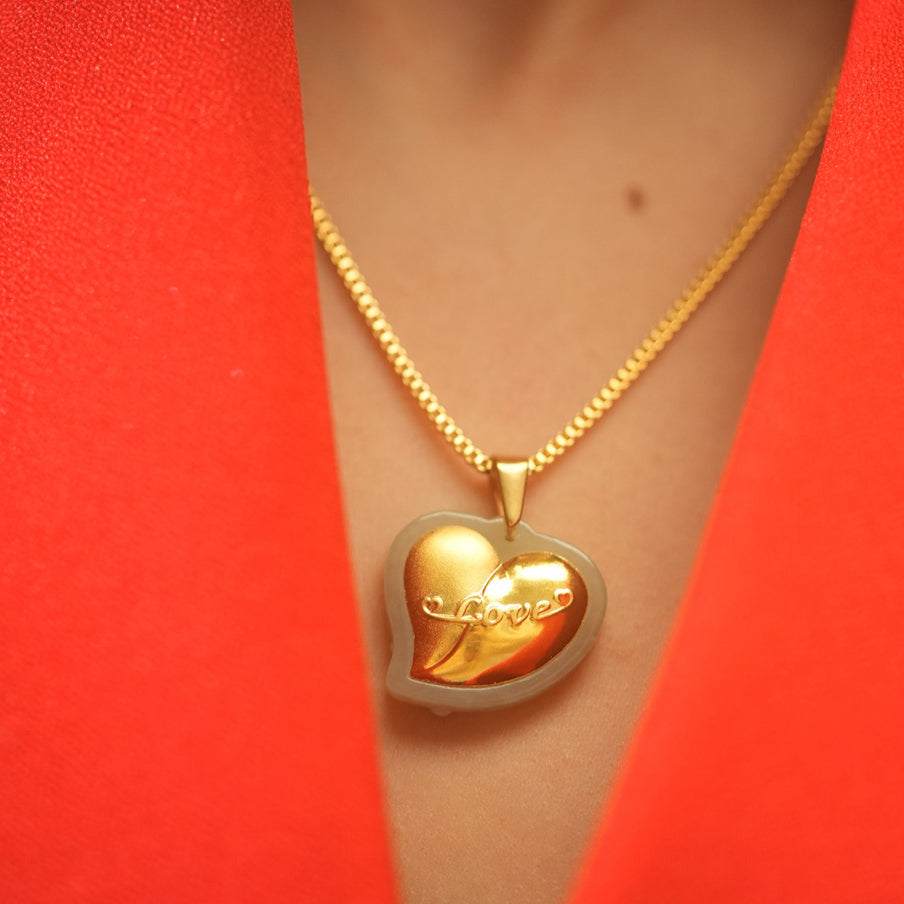 Gold heart-shaped pendant necklace on a person wearing a red garment.