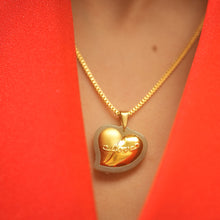 Gold heart-shaped pendant necklace on a person wearing a red garment.
