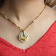 Gold necklace with a circular pendant featuring a ruby on a red top.