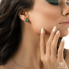 Woman wearing emerald green earrings with a close-up of the jewelry.