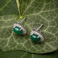 Green gemstone earrings with silver setting on a green leaf