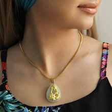 Woman wearing a gold necklace with a pendant, close-up on neck and shoulders.