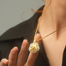 Gold necklace with a rose pendant worn by a person against a neutral background