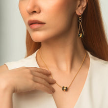 Woman wearing a gold necklace and earrings against a neutral background