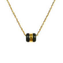 Necklace with black and gold cylindrical pendant on a white background
