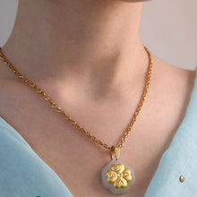 Gold necklace with a clover pendant worn by a person