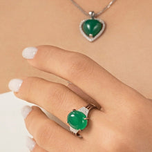 Close-up of hands wearing green gemstone rings with a visible brand logo.