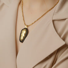 Gold necklace with a black pendant on a beige outfit